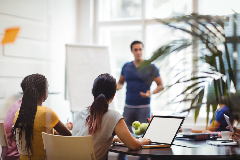 Business executives using laptop during meeting in office